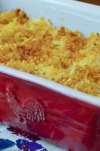 A red casserole dish full of cheesy hash browns with a browned topping.