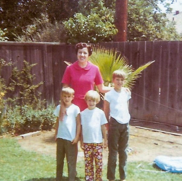 A woman standing with 3 children on a lawn.