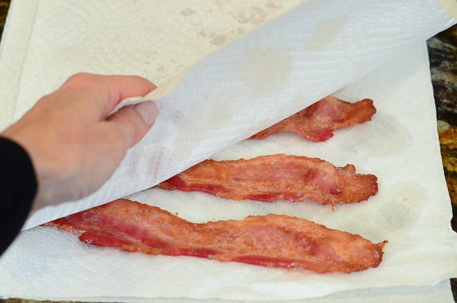 Blotting cooked bacon with additional paper towels.