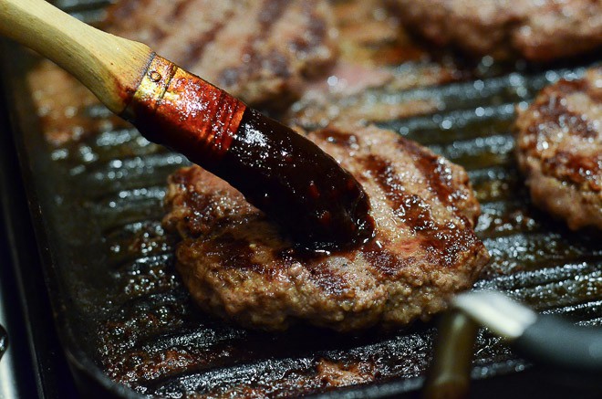 Brushing the burger patties with the Stout & Sriracha Barbecue Sauce