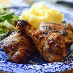 Grilled chicken that has been marinated in Pretty Chicken Marinade on a blue plate with mashed potatoes and salad.