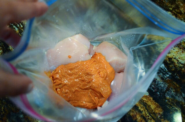 The greek yogurt marinade is added with the raw chicken inside a zippered bag.