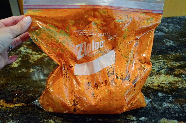 The chicken inside the plastic bag being evenly coated with marinade.