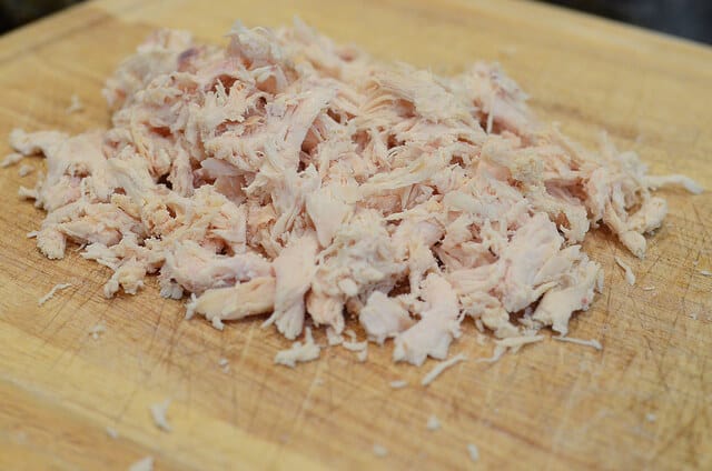 Shredded rotisserie chicken on a cutting board.