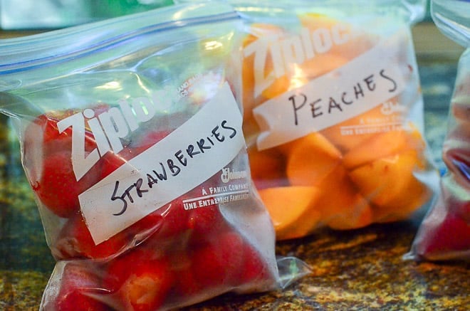 The flash frozen fruit is transferred to freezer safe plastic storage bags and labeled with a black permanent marker.