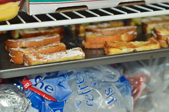 A baking sheet full of Nutella Stuffed French Toast Sticks inside a freezer.