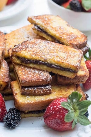 Nutella French Toast Sticks stacked on a plate with berries.
