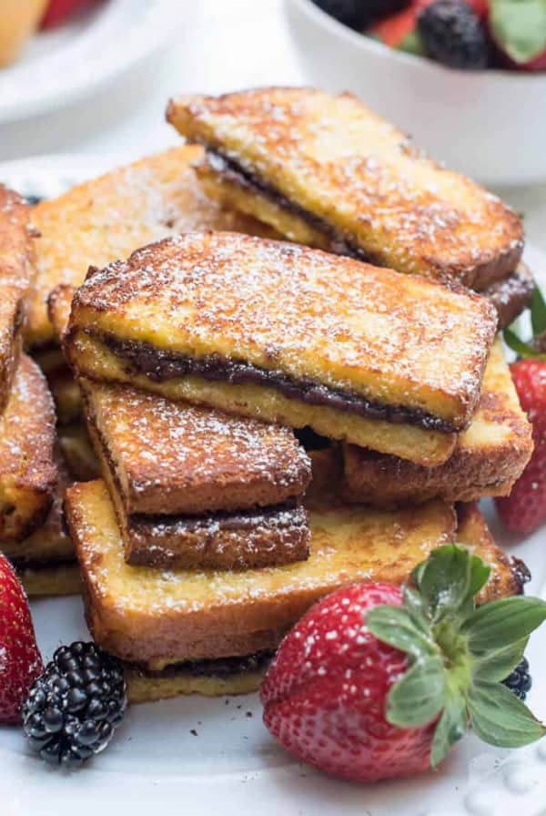 Nutella French Toast Sticks stacked on a plate with berries.