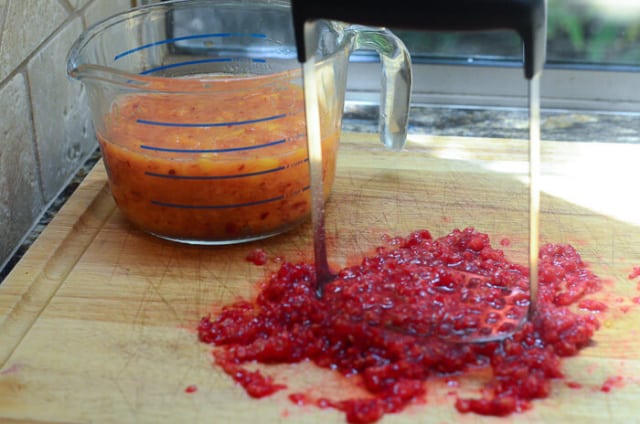 The fruit is being crushed with a potato masher.