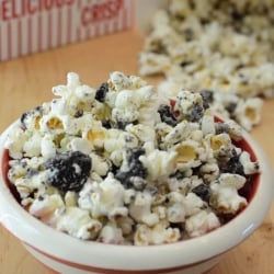 A bowl of white chocolate coated popcorn mixed with oreos in a bowl.