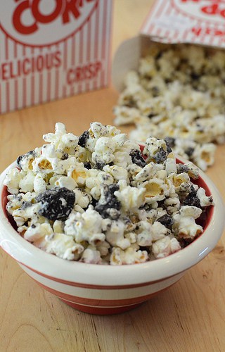 A bowl of white chocolate coated popcorn and oreo bits in a bowl.