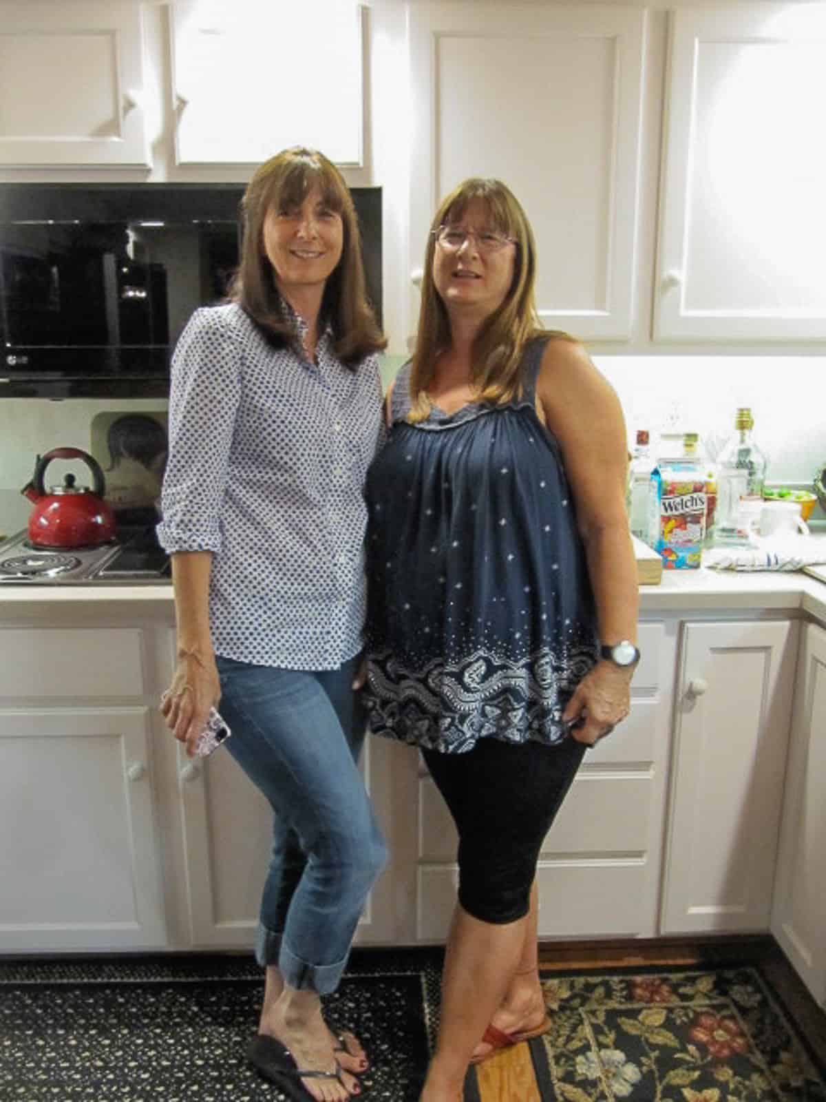 Two women posing for the camera in a kitchen.