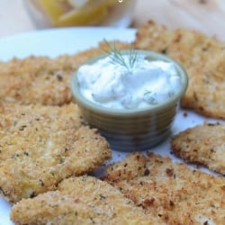 Breaded fish on a plate with creamy dill sauce.