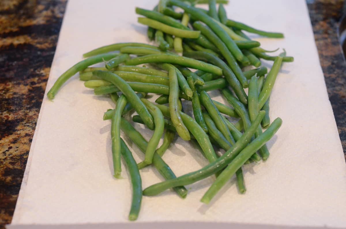 The partially cooked green beans draining on paper towels.