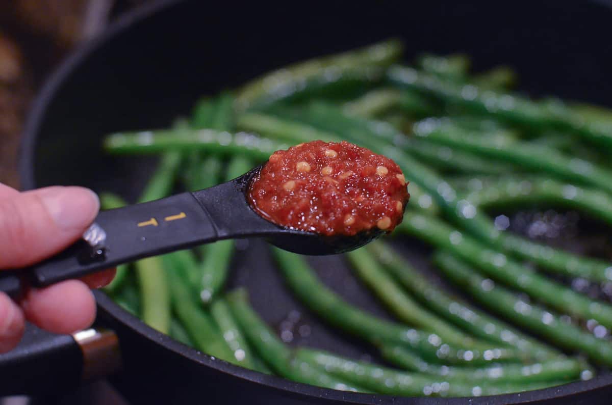 A tablespoon of chili garlic sauce is added to the skillet.