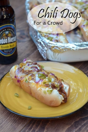 A yellow plate with a chili dog next to a beer.