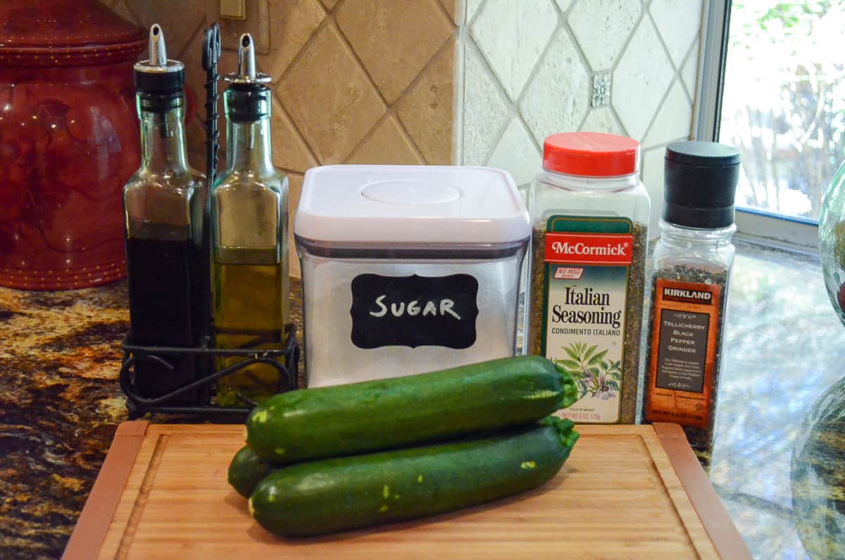 Zucchini, oil, balsamic vinegar, sugar, and seasoning on a kitchen counter.