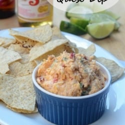 A blue ramekin filled with a cheese dip next to tortilla chips.