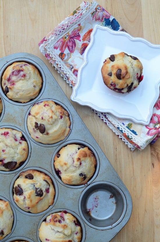 A muffin pan with one muffin missing and a white plate with a muffin.