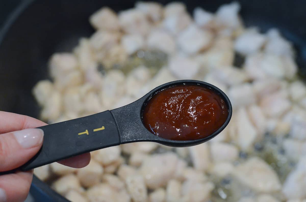 A measuring spoon full of BBQ sauce.