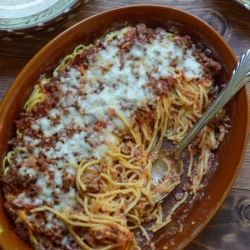 A baking dish with spaghetti and a spoon.