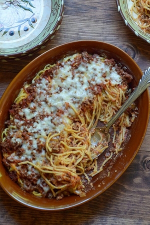 A baking dish filled with spaghetti casserole and a spoon.