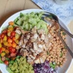 A white bowl filled with chicken and salad ingredients.