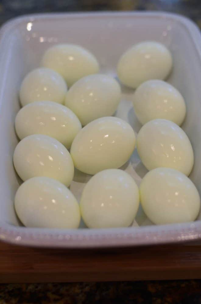 A white dish filled with peeled hard-boiled eggs.
