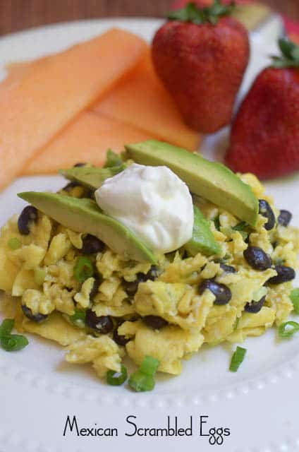 Mexican Scrambled Eggs on a white plate topped with avocado and sour cream.