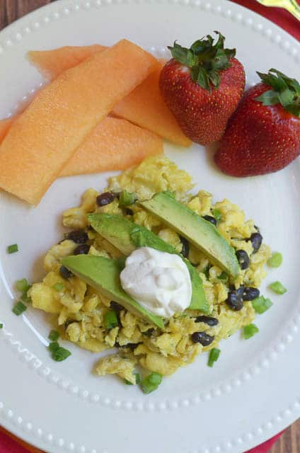 Mexican Scrambled Eggs on a white serving plate with fruit.