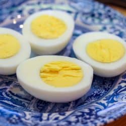 Hard boiled eggs sliced in half on a blue and white plate.