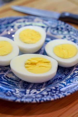 Hard boiled eggs sliced in half on a blue and white plate.