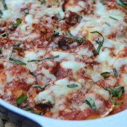 Ravioli topped with cheese in a baking dish.
