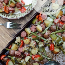Sausage, potatoes, and green beans on a baking sheet.
