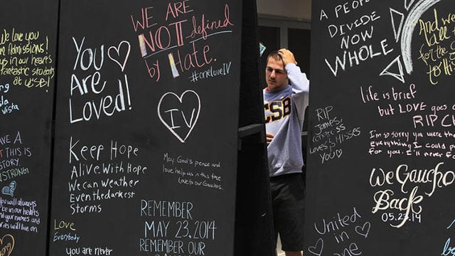 A man standing by blackboards with words on them outside.