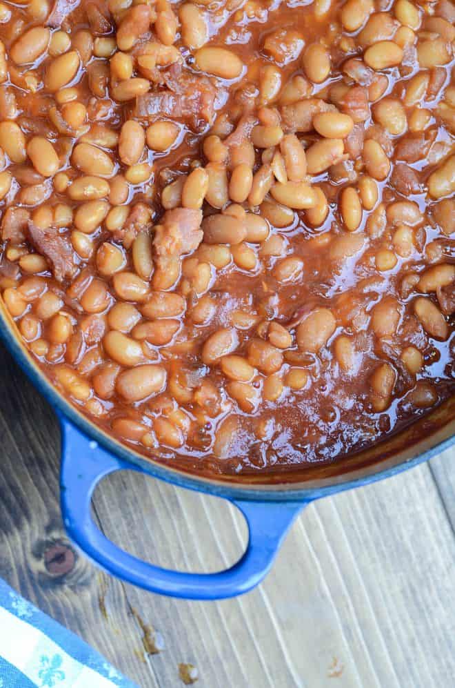 A close up image of old fashioned Baked Beans from Scratch in a blue Dutch oven shot from over the top.