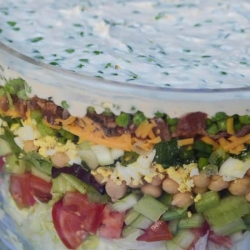 A close up of layered salad in a glass dish.