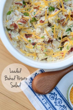 A bowl of potato salad topped with bacon and cheese.