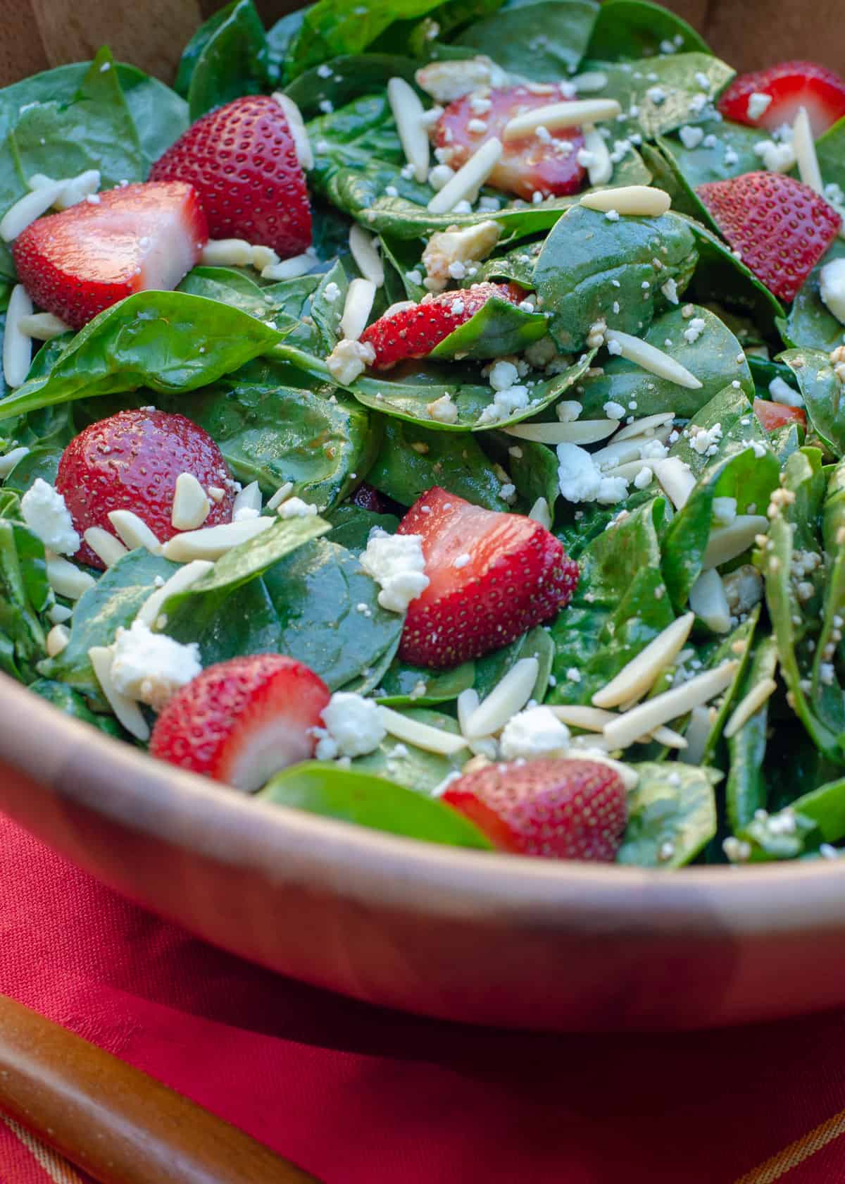 A close up of the Strawberry Spinach Salad in a wooden salad bowl.