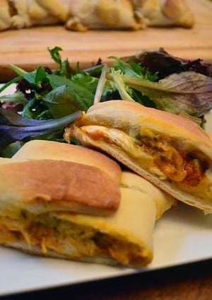 A calzone on a plate with a side of salad.