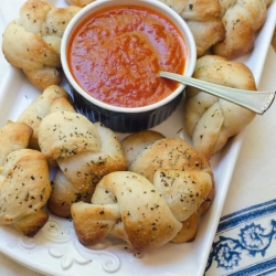 Garlic Parmesan Knots on a platter with marinara sauce.