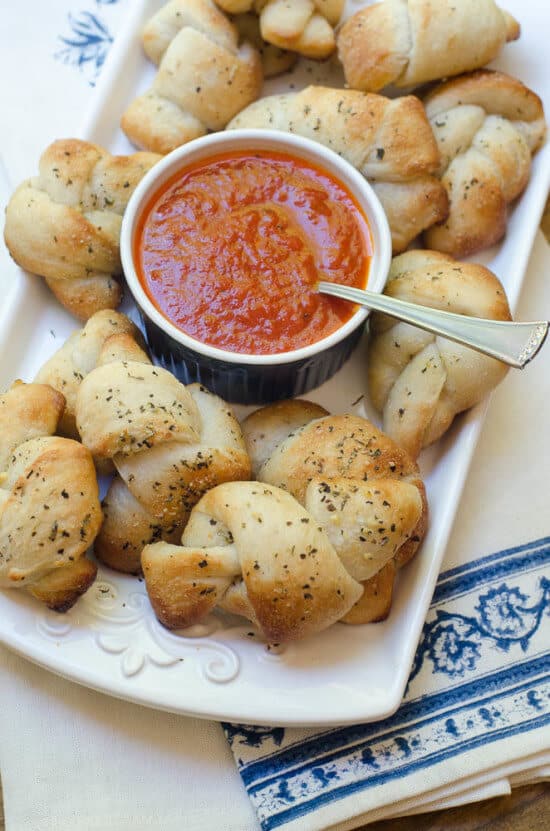 Garlic Parmesan Knots on a platter with marinara sauce.