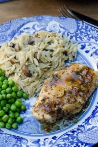 Chicken on a plate with rice and peas.