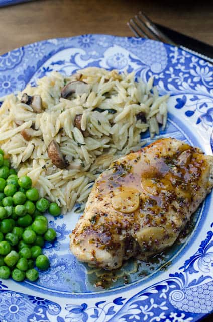 Chicken on a plate with rice and peas.