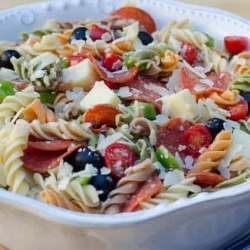 A bowl of pasta salad with pepperoni and tomatoes.
