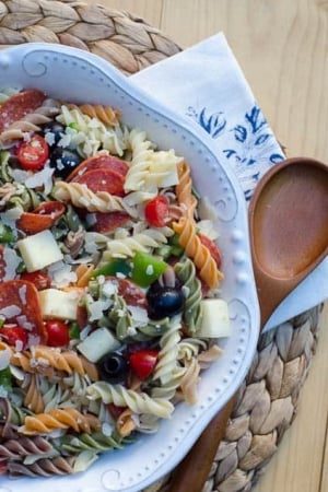 A bowl of pasta salad with olives, cheese, and pepperoni.