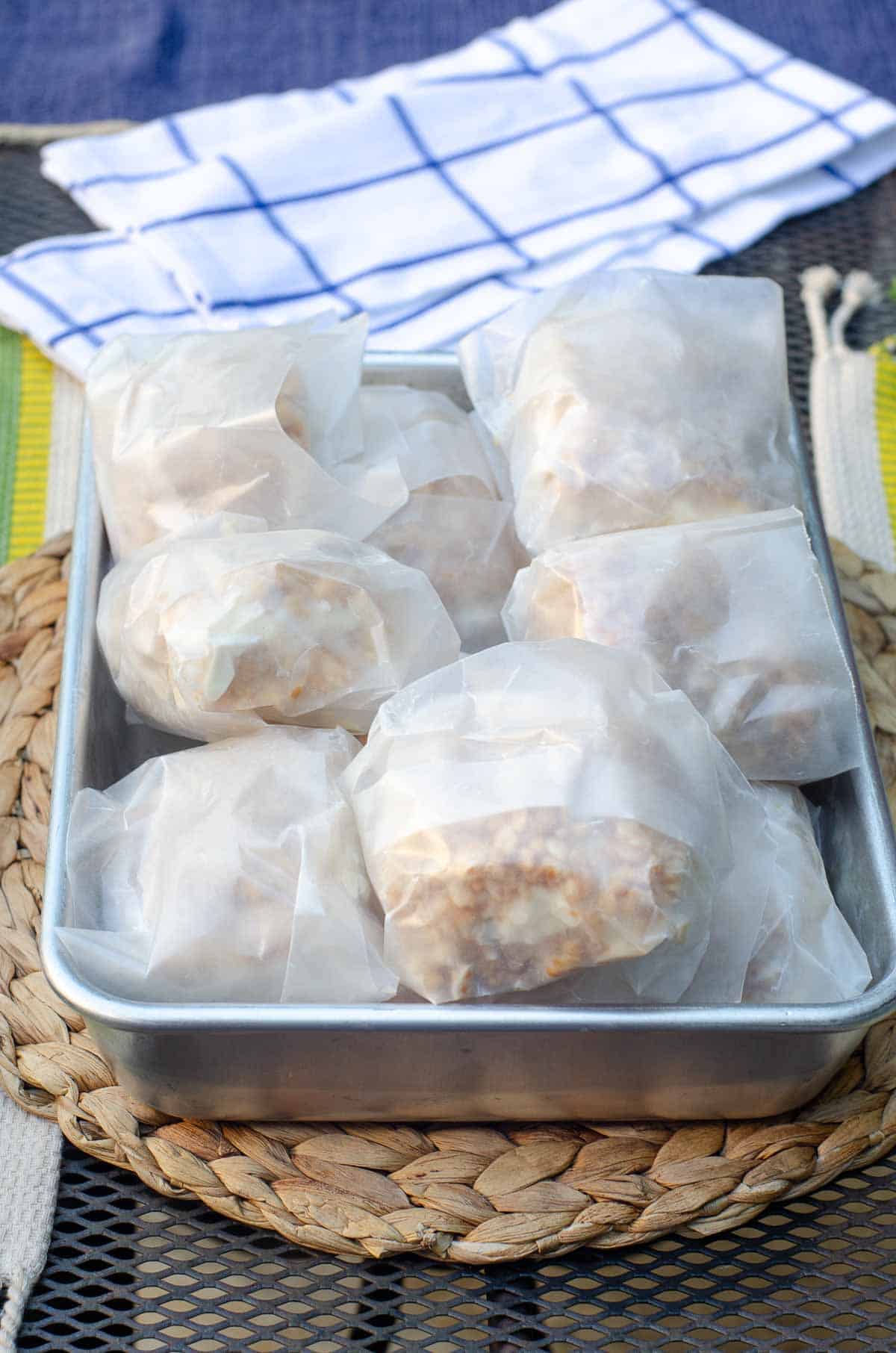 Rice Krispie ice cream sandwiches wrapped in wax paper and in a large metal pan.