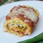 A close up of a chicken pesto lasagna rollup on a white plate.