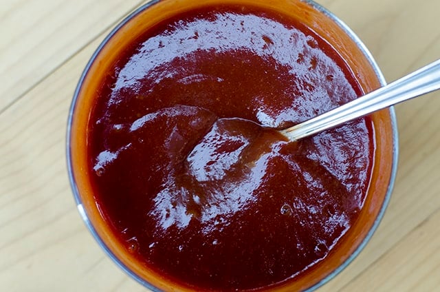 The BBQ glaze in a small bowl with a spoon.