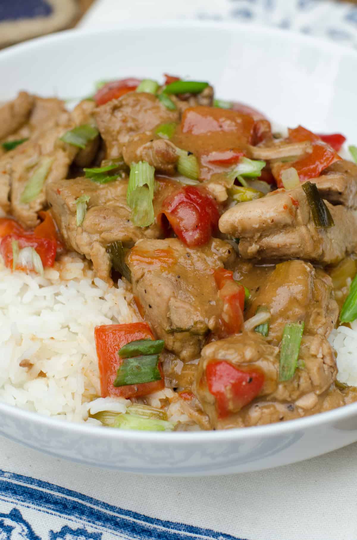 Slow Cooker Caribbean Pork over rice in a white serving bowl.